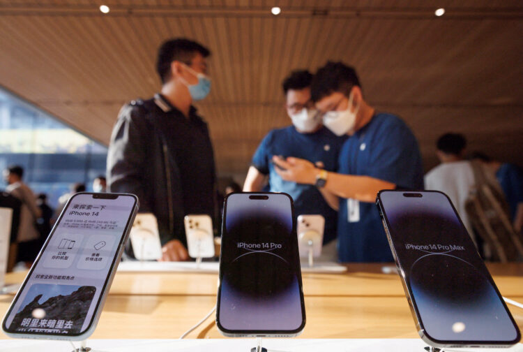 FILE PHOTO: A customer talks to sales assistants in an Apple store as Apple Inc's new iPhone 14 models go on sale in Beijing, China, September 16, 2022. REUTERS/Thomas Peter/File Photo